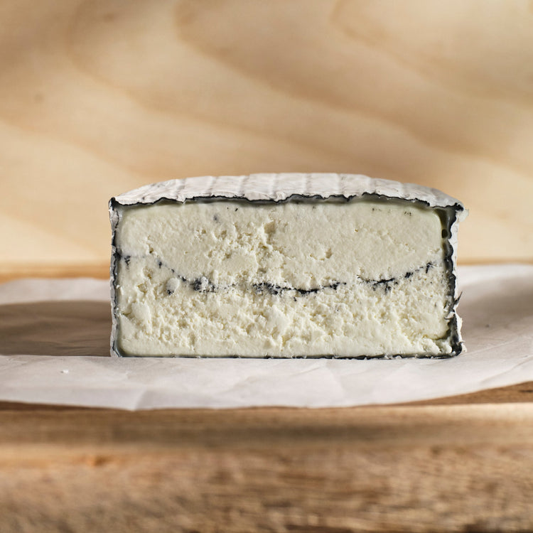 Half-cut cheese on a wooden board with a wooden background