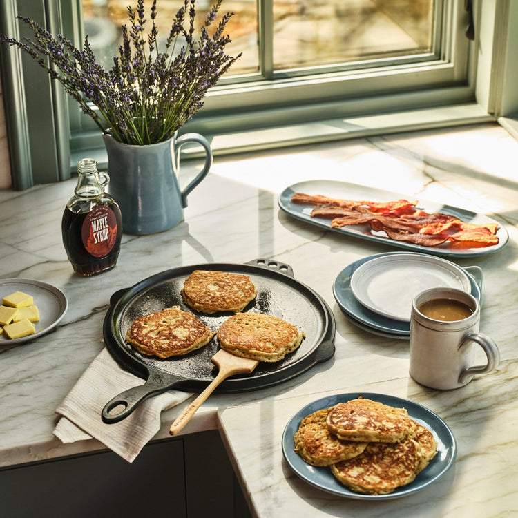 Breakfast scene with pancakes, bacon, and coffee on a kitchen counter.