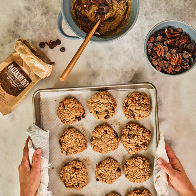 Baked cookies on a tray with ingredients and a bowl of cookie dough.