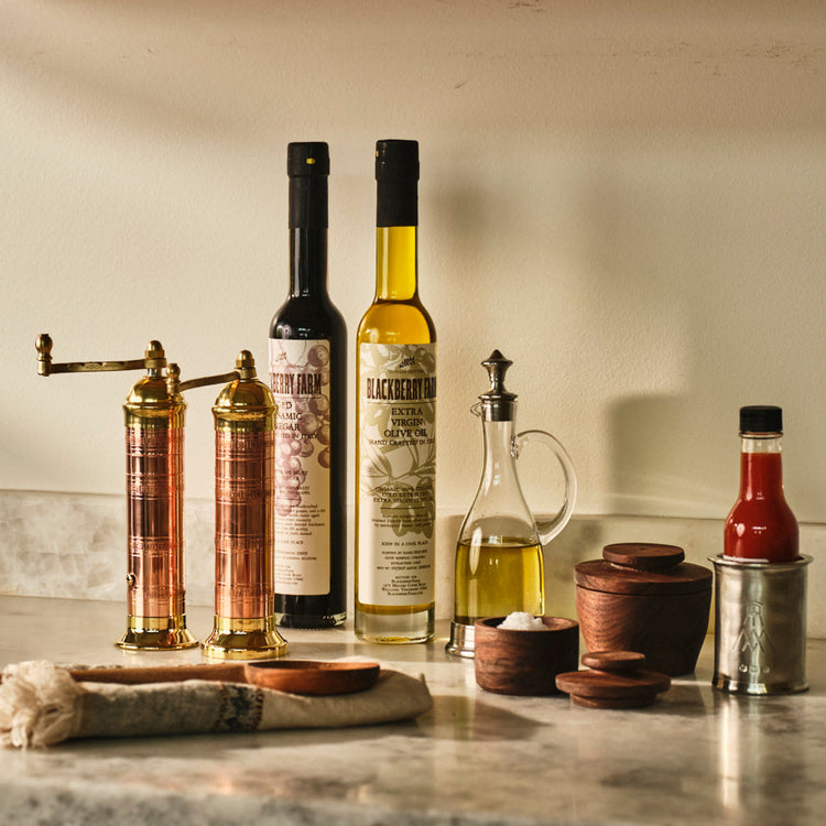 Bottles of olive oil and vinegar on a kitchen counter with wooden cabinets in the background.