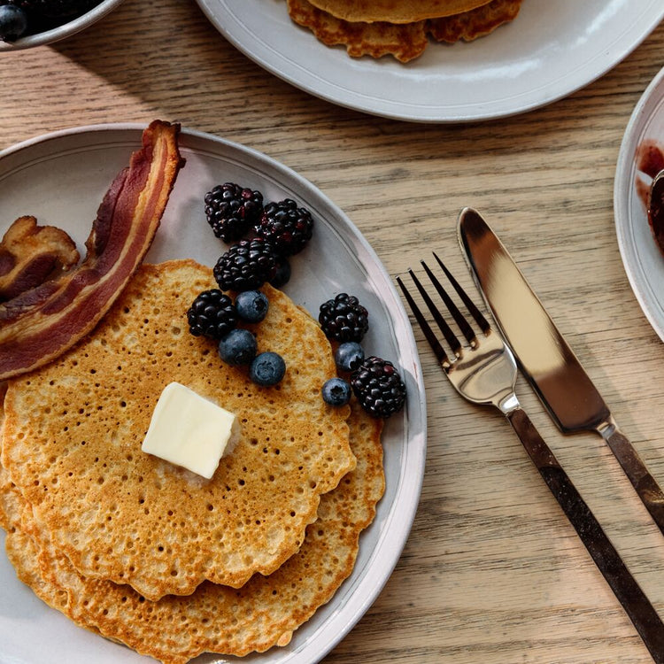 Stacks of pancakes with berries and bacon on a wooden table