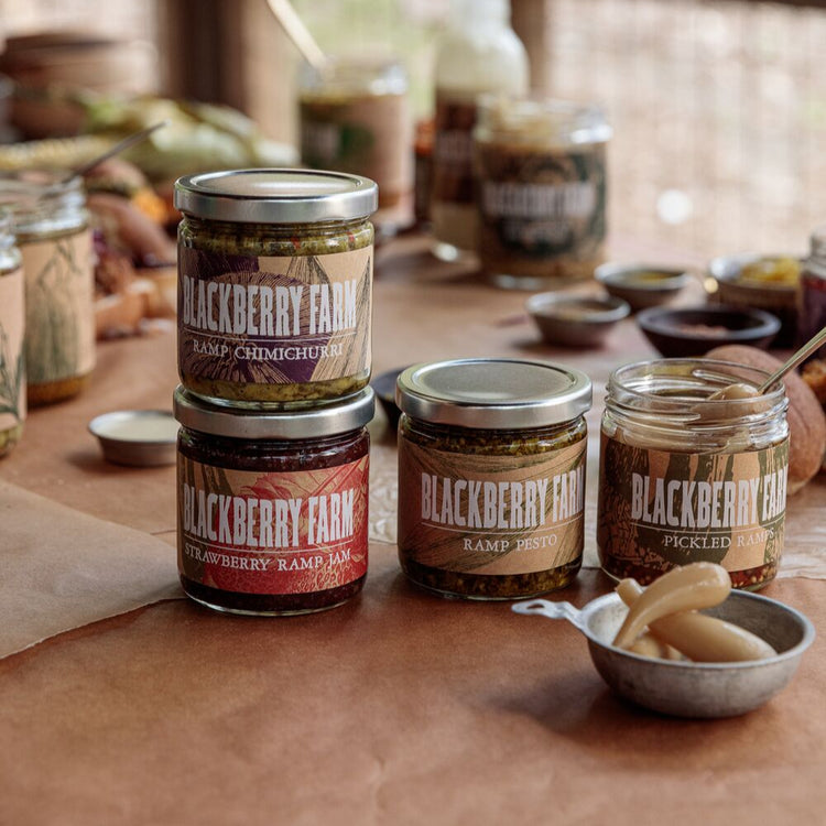 Jars of Blackberry Farm pickles on a wooden table with a rustic background.