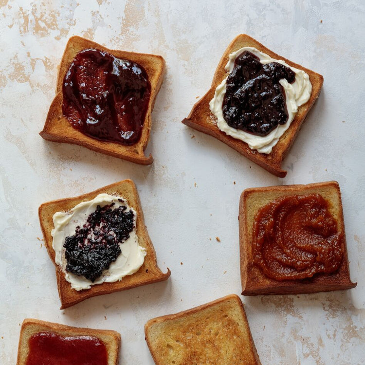 Toast squares with different types of spreads and jam on a textured surface