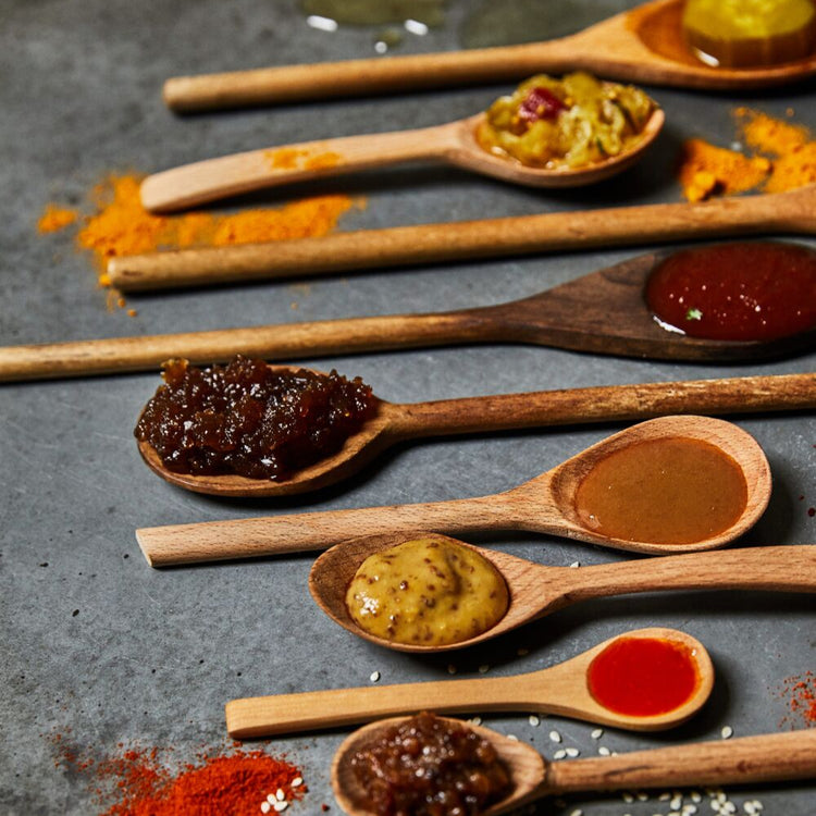 Wooden spoons with various condiments on a textured surface
