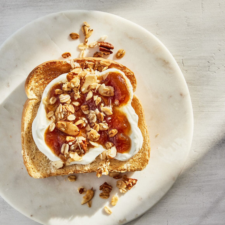 Toast with cream cheese, jam, and nuts on a marble plate